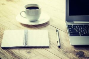 Carnet ouvert à côté d’un stylo, d’une tasse de café et d’un ordinateur portable, prêt pour réviser la conjugaison espagnole