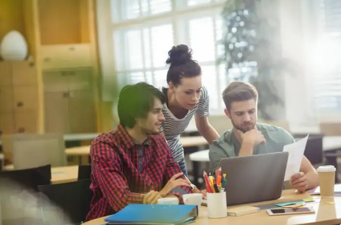 Trois collègues travaillent ensemble autour d’un ordinateur portable